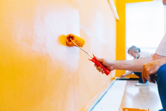 dos pintores pintando una pared de amarillo